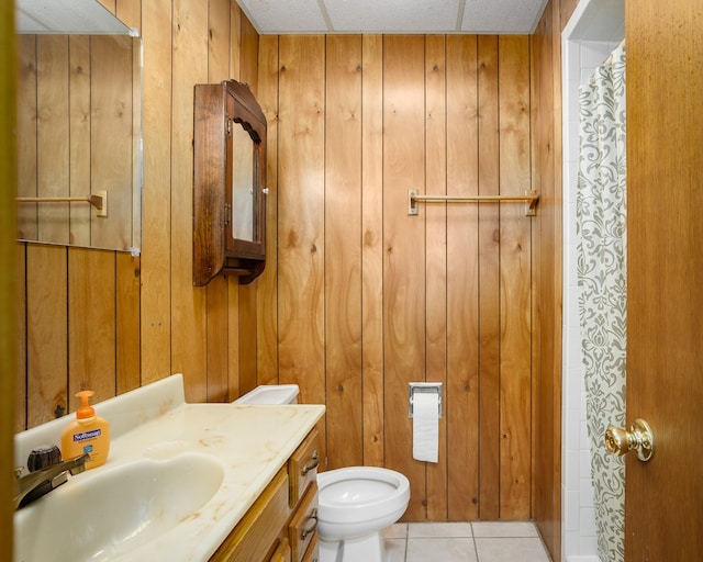 bathroom with tile patterned flooring, wooden walls, toilet, and vanity