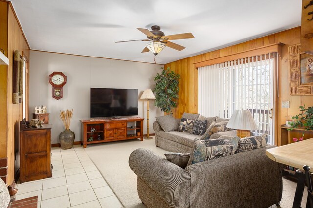 tiled living area featuring a ceiling fan and wooden walls