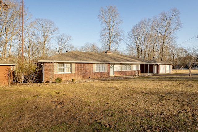 single story home with brick siding, a chimney, and a front yard