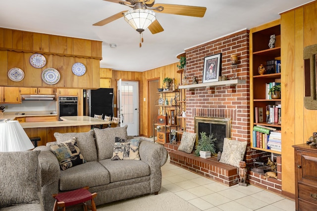 living area featuring light tile patterned floors, ceiling fan, a fireplace, and wooden walls