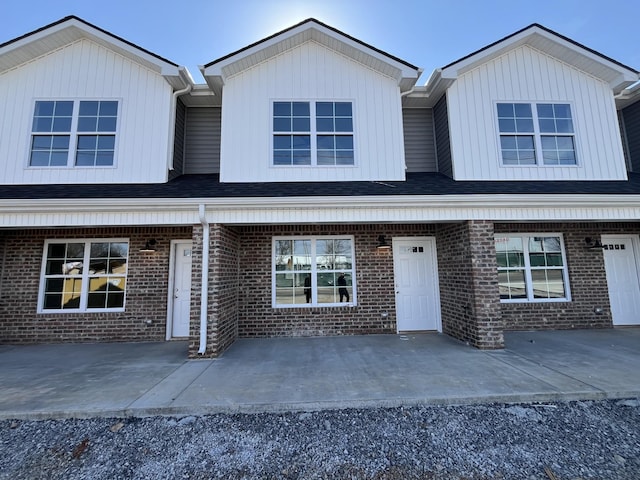 view of property with brick siding and roof with shingles