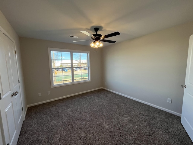 unfurnished bedroom with a ceiling fan, visible vents, dark carpet, and baseboards