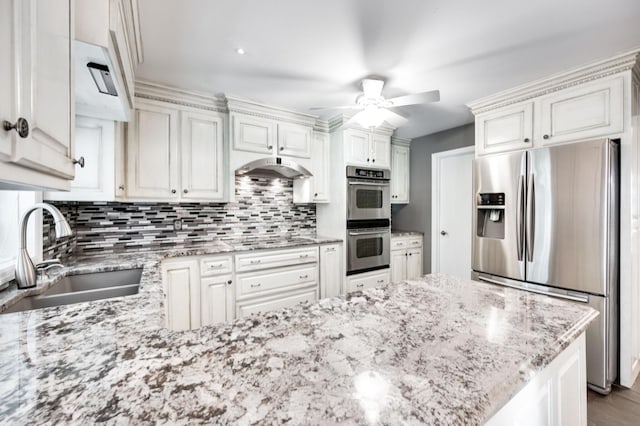 kitchen with tasteful backsplash, appliances with stainless steel finishes, a sink, a peninsula, and under cabinet range hood