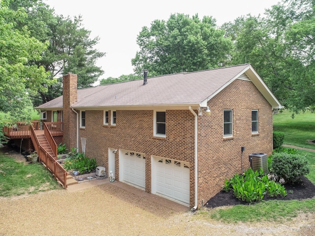 view of side of home featuring brick siding, a chimney, stairway, a garage, and driveway