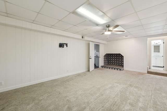 below grade area with carpet, a paneled ceiling, visible vents, a ceiling fan, and baseboards