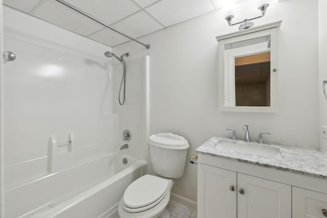 full bathroom featuring baseboards, a drop ceiling, toilet, tub / shower combination, and vanity