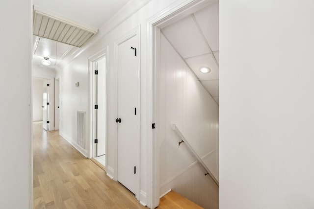 corridor featuring attic access, light wood-type flooring, visible vents, and an upstairs landing