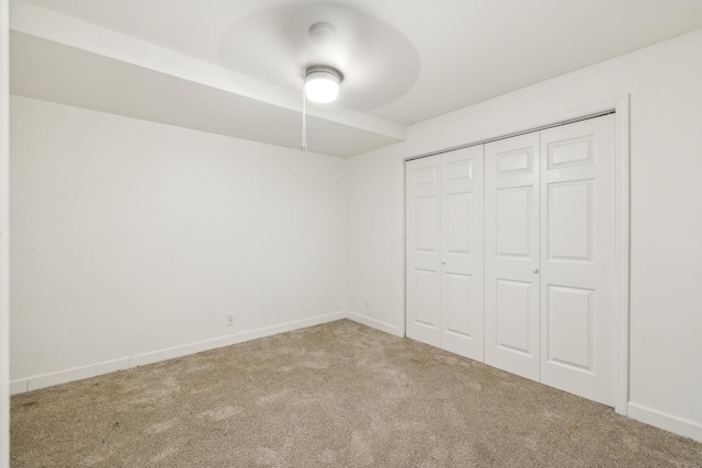 unfurnished bedroom with carpet, a closet, ceiling fan, and baseboards