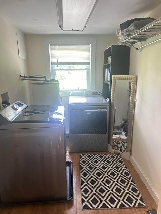 clothes washing area featuring laundry area, baseboards, separate washer and dryer, and wood finished floors