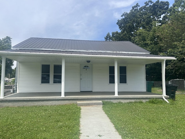 bungalow featuring covered porch, metal roof, and a front lawn