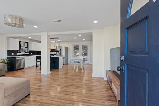 interior space with recessed lighting, visible vents, baseboards, french doors, and light wood finished floors