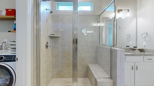 bathroom featuring washer / dryer, vanity, and a stall shower