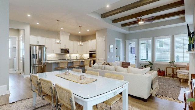 dining area with ceiling fan, recessed lighting, baseboards, light wood-style floors, and beamed ceiling