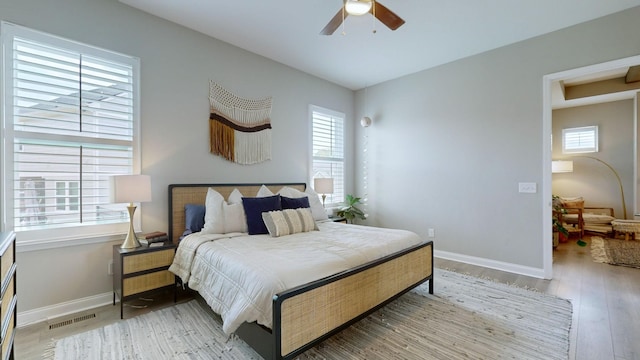 bedroom featuring light wood-type flooring, baseboards, multiple windows, and visible vents