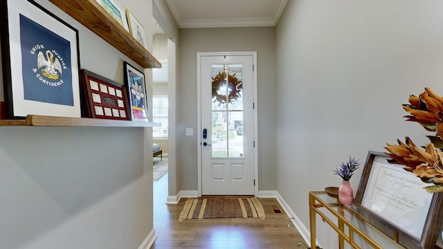 doorway featuring baseboards, wood finished floors, and crown molding