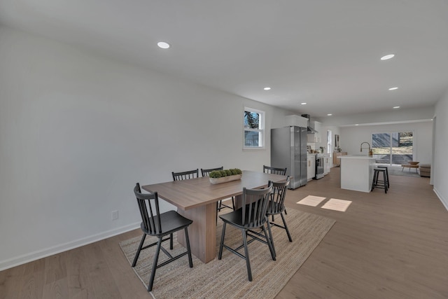 dining room with recessed lighting, light wood-style flooring, and baseboards