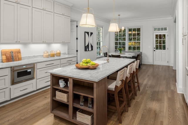 5042 Hill Place Dr, Nashville, TN 37205 - kitchen featuring dark wood-style flooring, ornamental molding, open shelves, a center island with sink, and pendant lighting