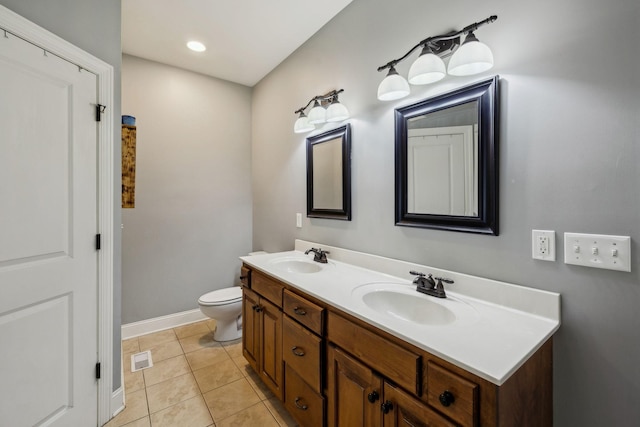 bathroom with double vanity, toilet, a sink, and tile patterned floors