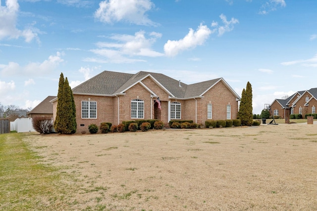 view of front facade with brick siding, roof with shingles, and fence