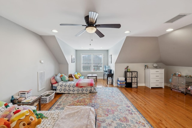 bedroom with lofted ceiling, wood finished floors, visible vents, and baseboards