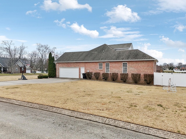 view of home's exterior featuring a garage, concrete driveway, fence, a yard, and brick siding