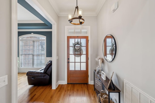 entrance foyer featuring a wealth of natural light, wood finished floors, visible vents, and crown molding