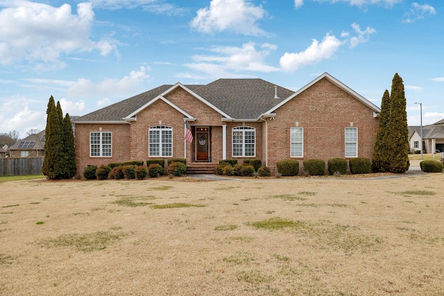 ranch-style home featuring brick siding and fence