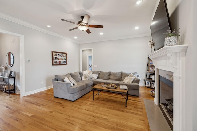 living room with a high end fireplace, a ceiling fan, light wood-style flooring, crown molding, and recessed lighting