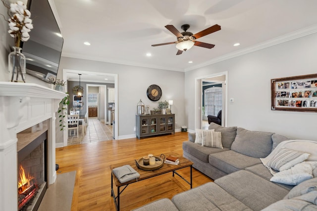 living room with recessed lighting, a premium fireplace, light wood-style floors, ornamental molding, and baseboards