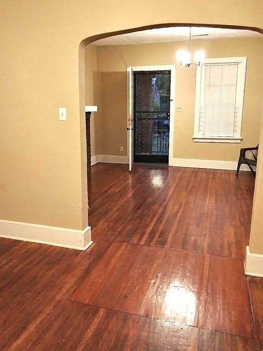 interior space with a notable chandelier, baseboards, arched walkways, and wood finished floors