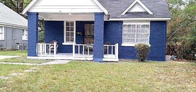 exterior space with covered porch, a front lawn, and brick siding