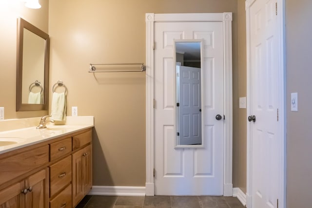 full bathroom with baseboards, double vanity, a sink, and tile patterned floors