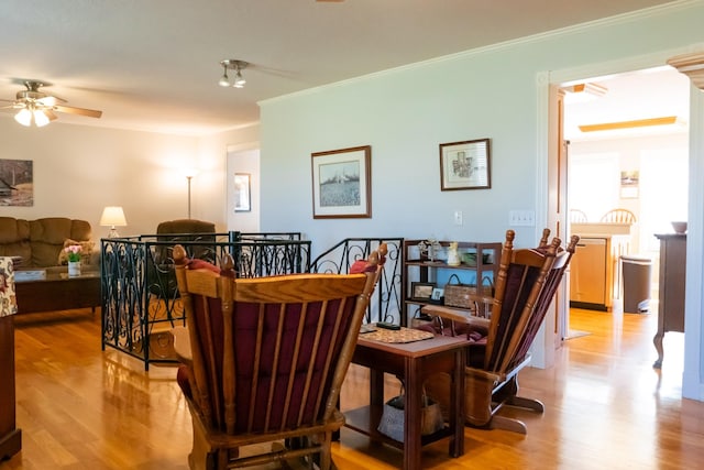 living room featuring light wood-style floors, ornamental molding, and a ceiling fan