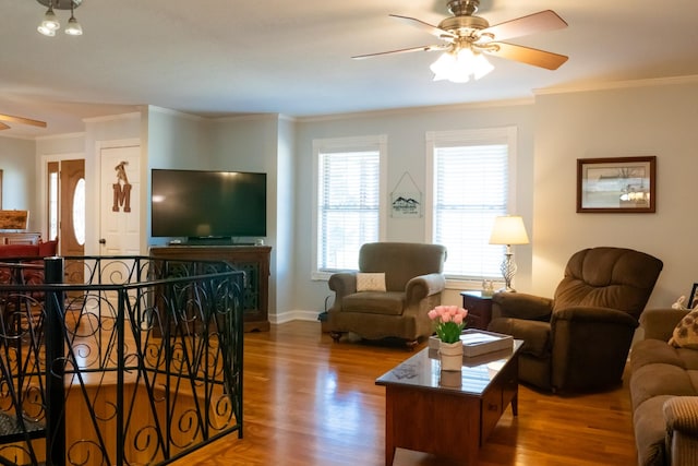 living room with a ceiling fan, ornamental molding, and wood finished floors