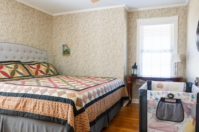 bedroom featuring ornamental molding, wood finished floors, and wallpapered walls