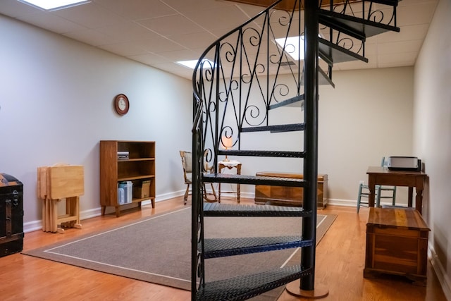 staircase with a drop ceiling, baseboards, and wood finished floors