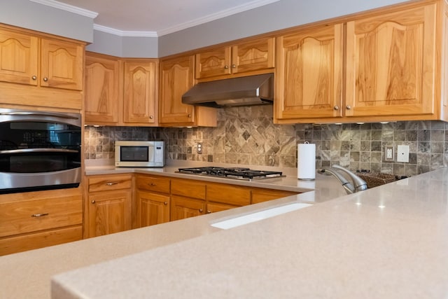 kitchen featuring crown molding, stainless steel appliances, light countertops, and under cabinet range hood