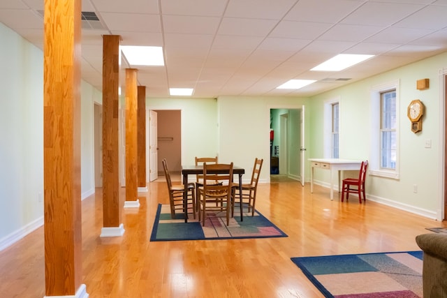 dining space with a paneled ceiling, baseboards, and wood finished floors