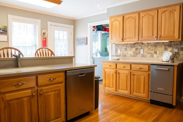 kitchen with washer and clothes dryer, light wood-style flooring, ornamental molding, a sink, and dishwasher