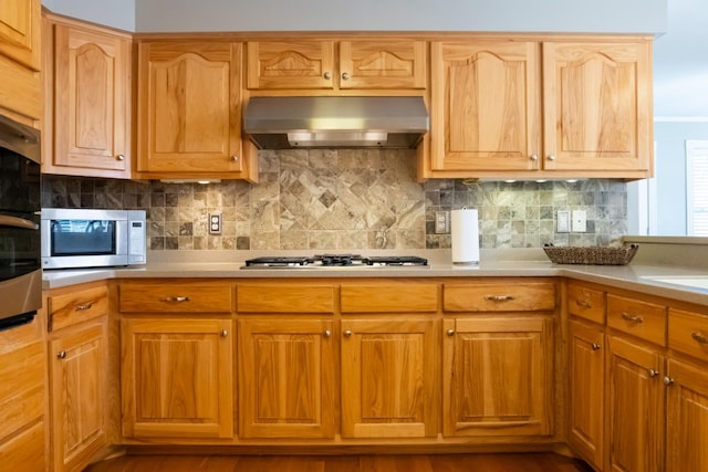 kitchen featuring stainless steel appliances, extractor fan, light countertops, and decorative backsplash