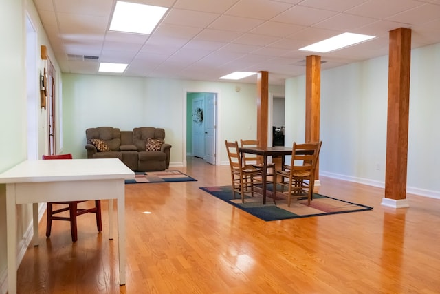 dining space featuring a paneled ceiling, visible vents, baseboards, and wood finished floors