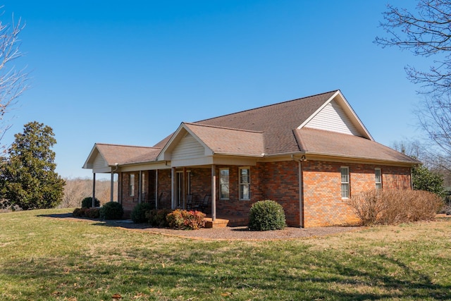 view of side of property featuring a yard, a porch, and brick siding