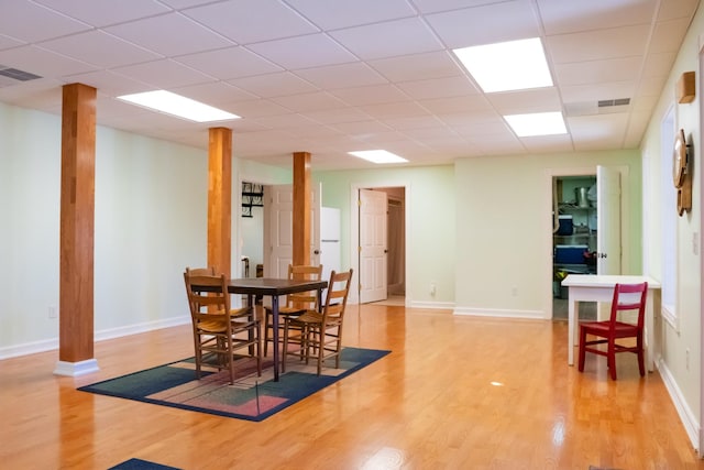 dining area with a paneled ceiling, visible vents, light wood-style flooring, and baseboards