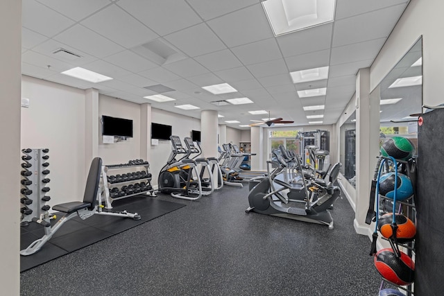 gym with a paneled ceiling, visible vents, and ceiling fan