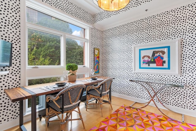 dining space featuring baseboards, crown molding, light wood finished floors, and wallpapered walls