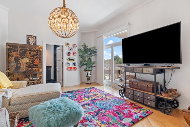 living area with a chandelier, crown molding, baseboards, and wood finished floors