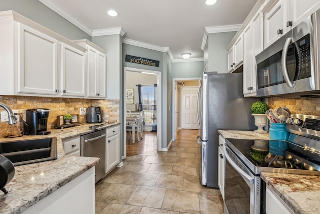 kitchen featuring decorative backsplash, white cabinets, appliances with stainless steel finishes, ornamental molding, and a sink