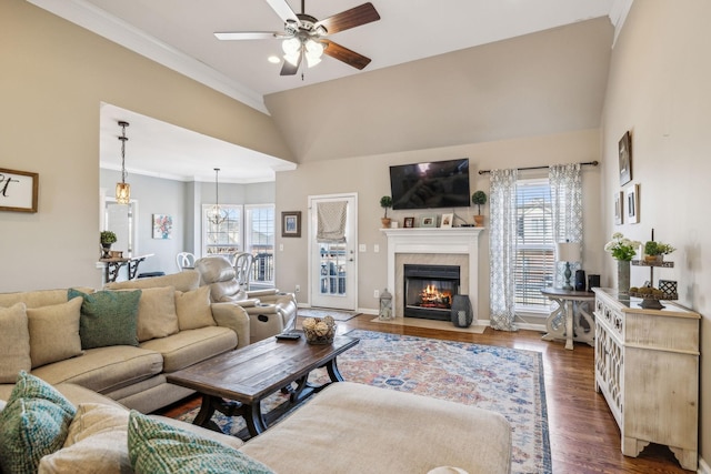 living room with lofted ceiling, a fireplace with flush hearth, baseboards, ornamental molding, and dark wood finished floors