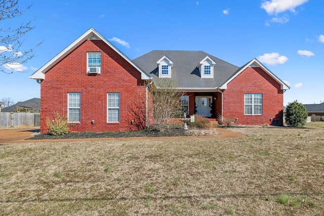 traditional-style home with brick siding, a front yard, and fence