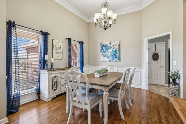 dining room with a notable chandelier, wainscoting, wood finished floors, and crown molding